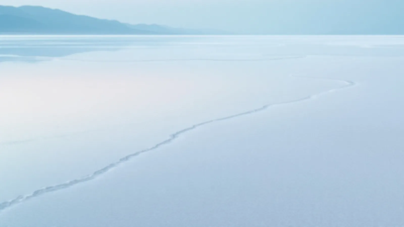 A wide pale salt flat with a thin layer of water reflecting a soft blue sky at dawn, the CoupeRates view of find loan rates online, $100 – $5,000